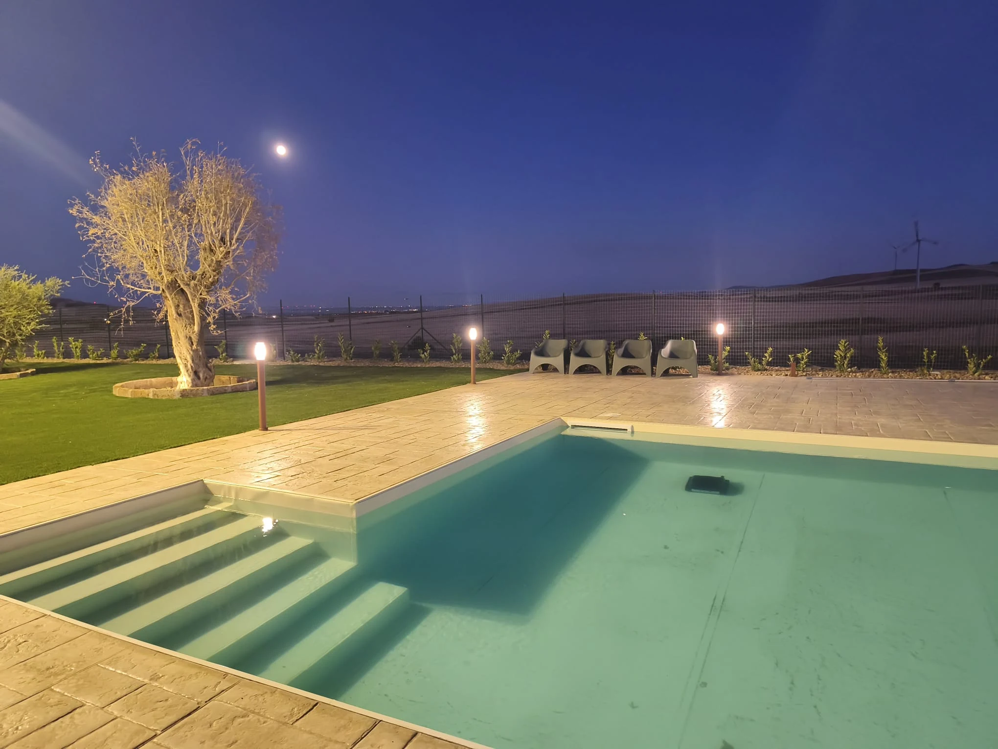 Piscina illuminata con gradini di accesso e solarium